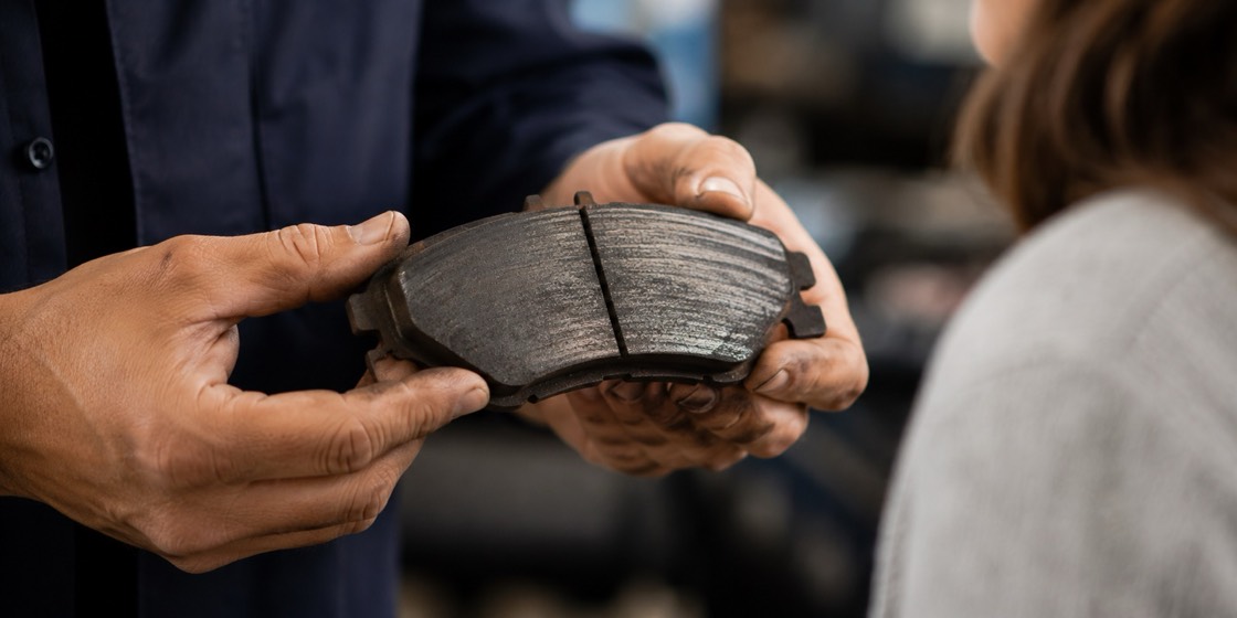 A mechanic showing a worn brake pad to a customer