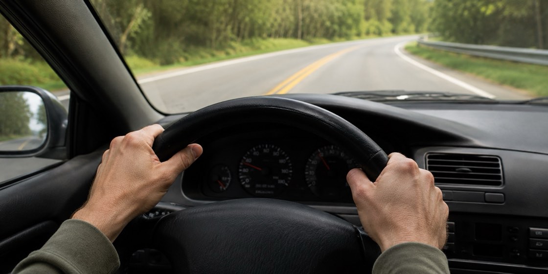 A driver's hands on the steering wheel as the car pulls to one side