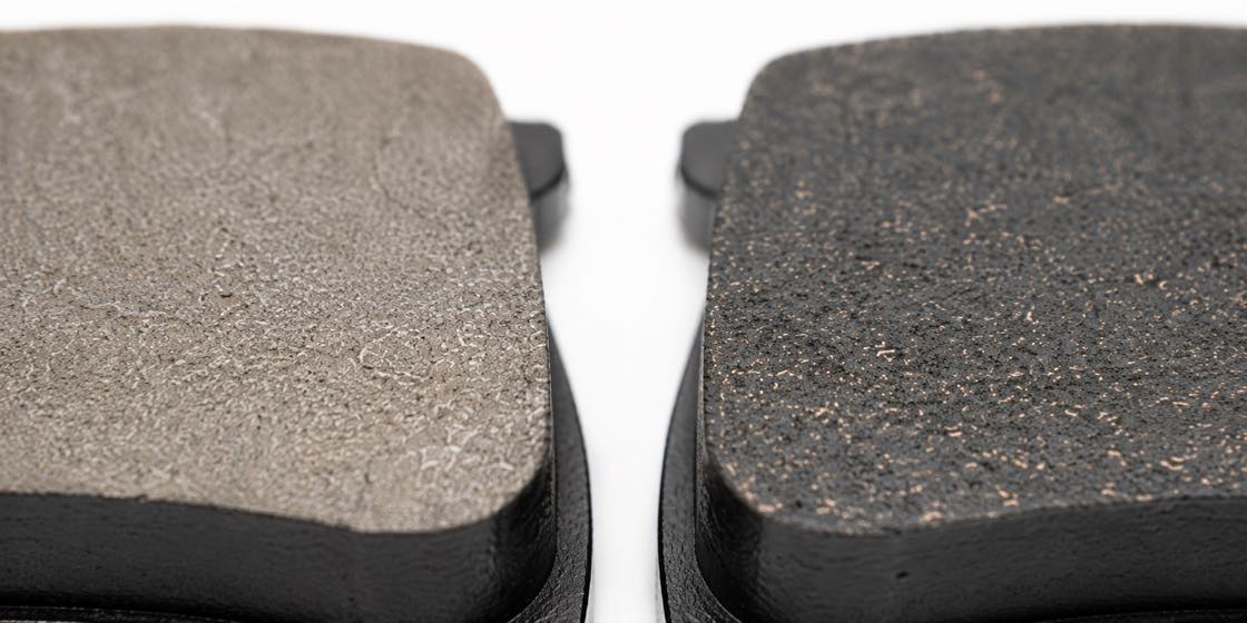 The friction surfaces of a ceramic brake pad and a semi-metallic one side by side
