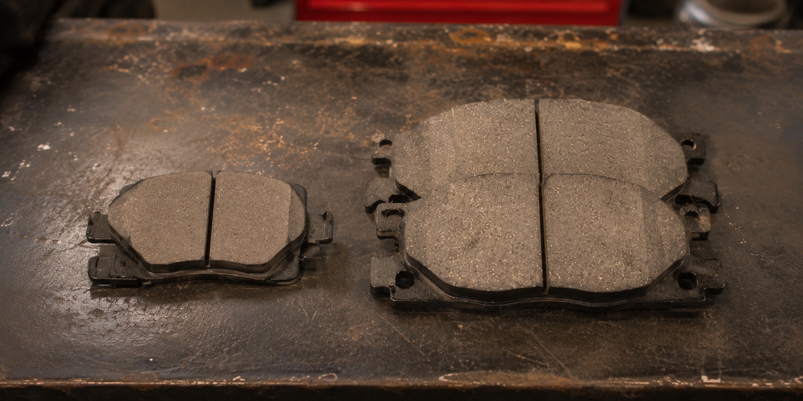 Two sets of new front brake pads laid side by side on the workbench at Dad's Auto Repair in Southwest Atlanta