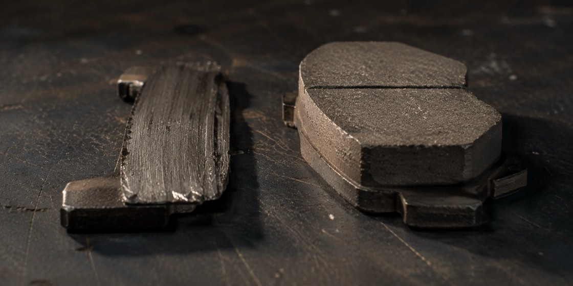 A brake pad worn down beside a healthy thick one for comparison