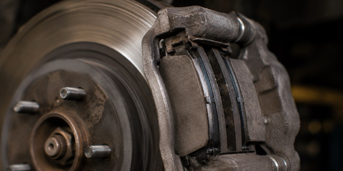 A brake caliper squeezing two brake pads against a spinning rotor