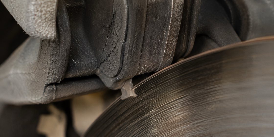 A worn brake pad with the metal wear-indicator tab nearly touching the rotor